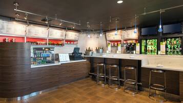 A modern bar area with a wooden counter, multiple stools, and overhead lighting.