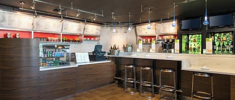 A modern bar area with a wooden counter, multiple stools, and overhead lighting.