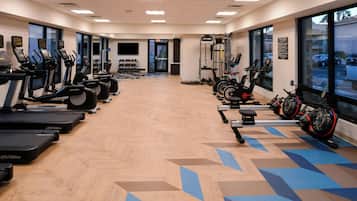 Un gimnasio con cintas de correr, elípticas y máquinas de pesas.
