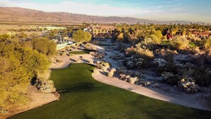 A golf course with a clubhouse, desert vegetation, and distant mountains. - Courtyard by Marriott Palm Desert (Palm Desert)