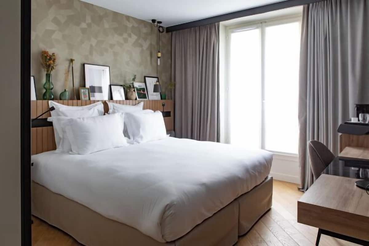 Habitación de hotel con una cama grande, un escritorio y una ventana con cortinas.