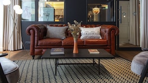 A modern living room with a leather sofa, a coffee table, and a vase with dried flowers. - Maison Mère (Paris)