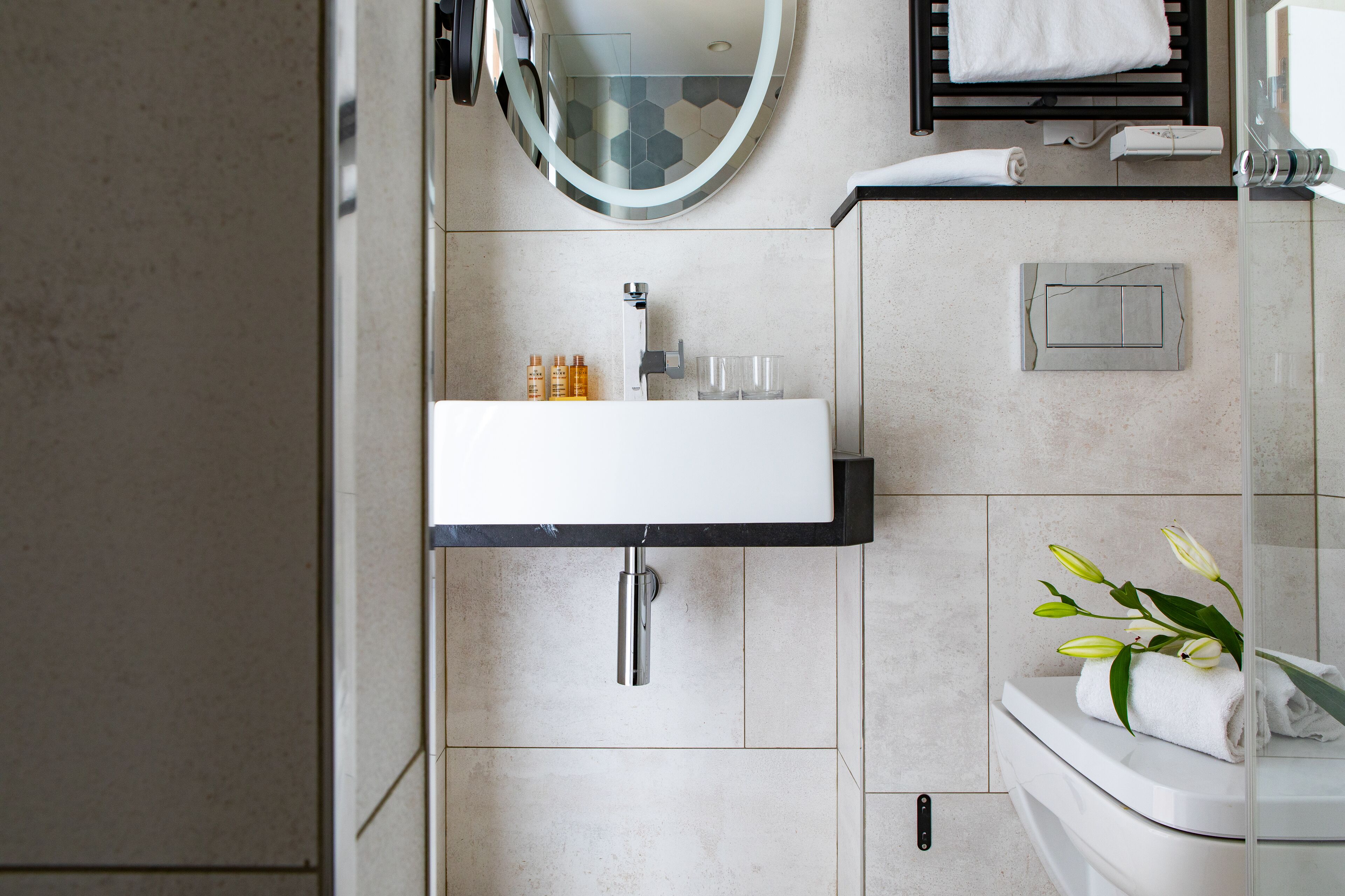 Un baño moderno con lavabo, espejo y retrete blancos.