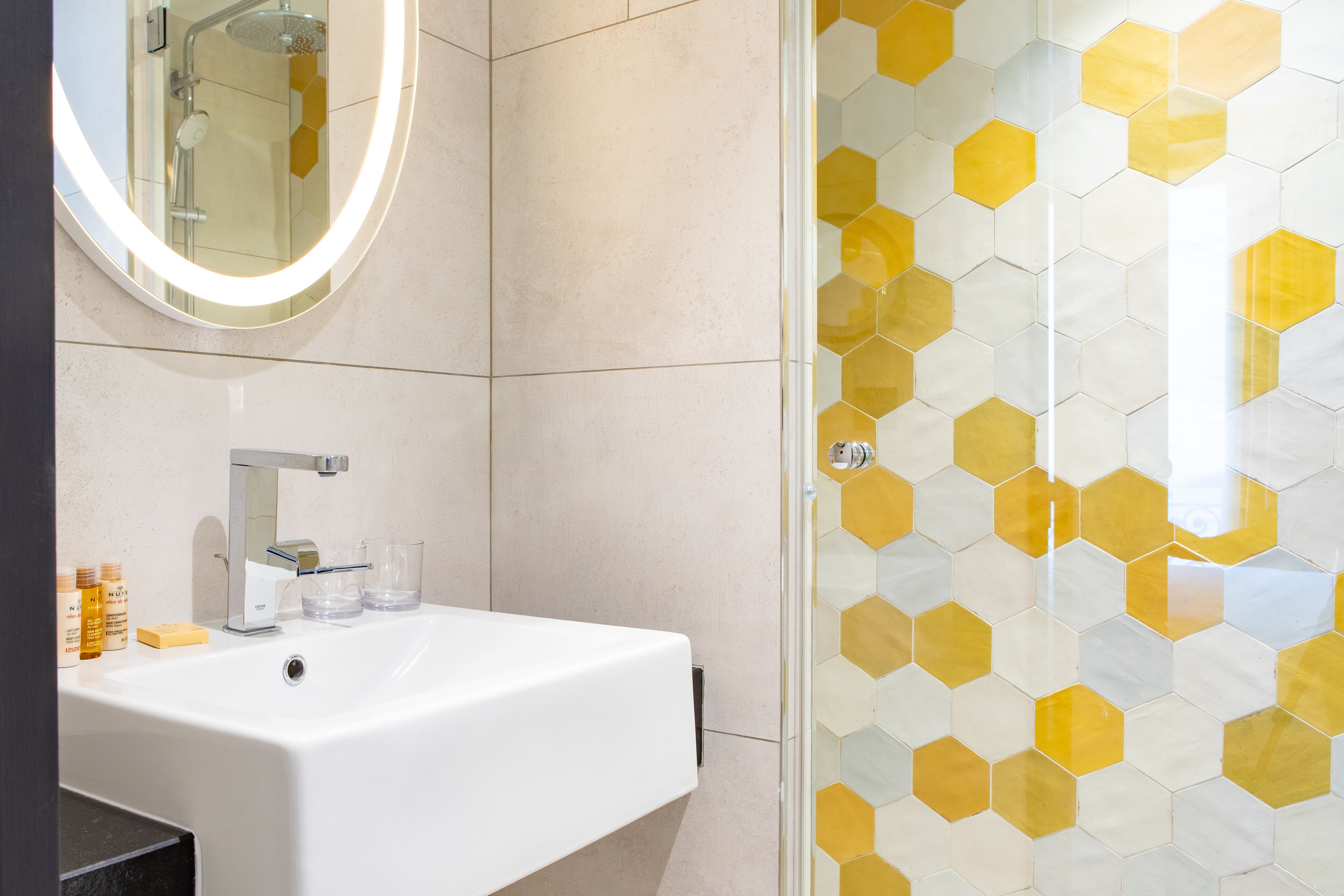 A bathroom with a white sink, a mirror, and a shower with a glass door.