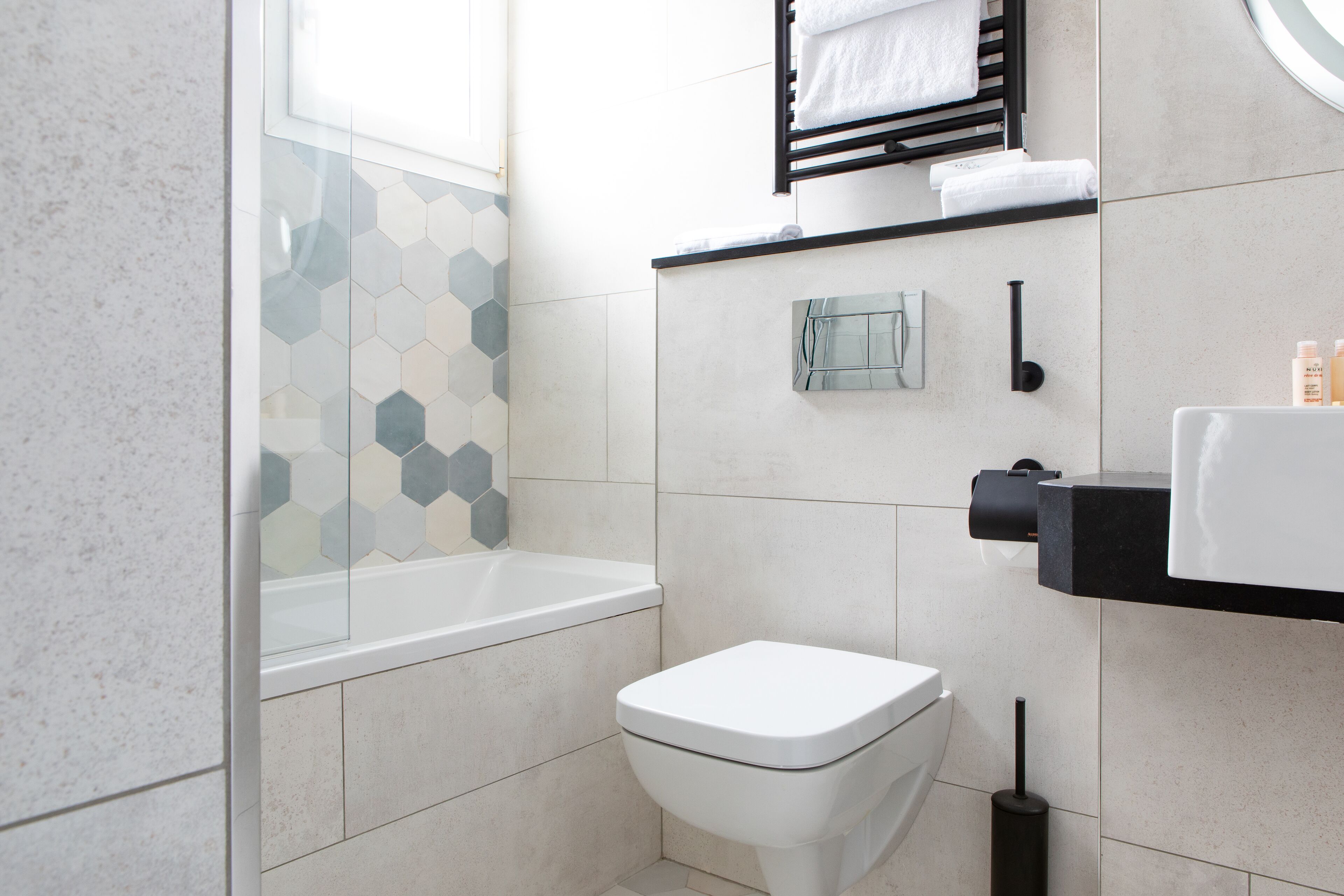 A modern bathroom with a white toilet, a glass shower enclosure, and a black towel rack.