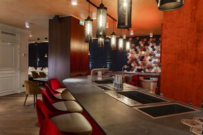 A modern bar area with a long counter, multiple seating options, and stylish pendant lighting.