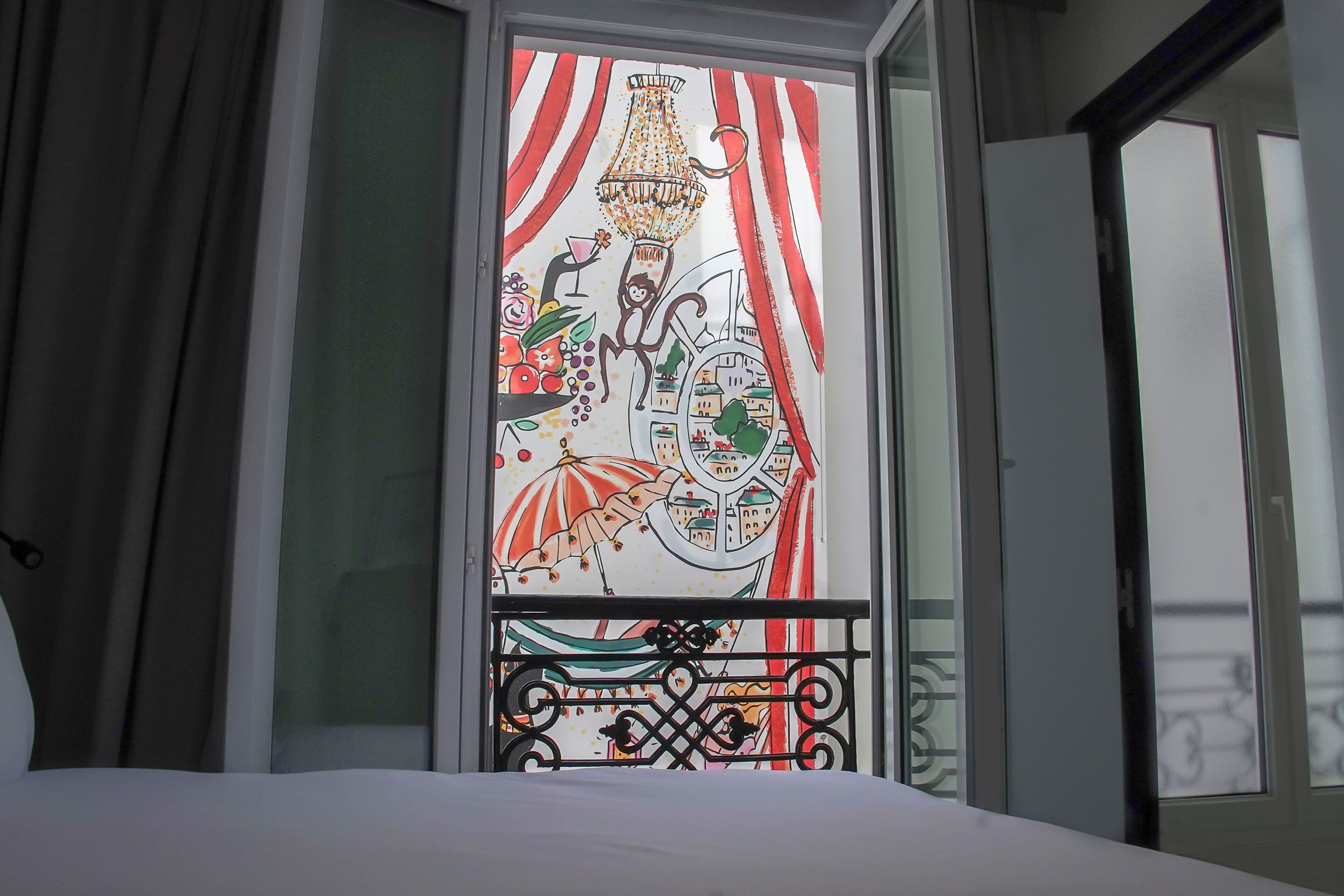 Ein Zimmer mit einem Bett, einem Fenster mit farbigem Glasdekor und Vorhängen.