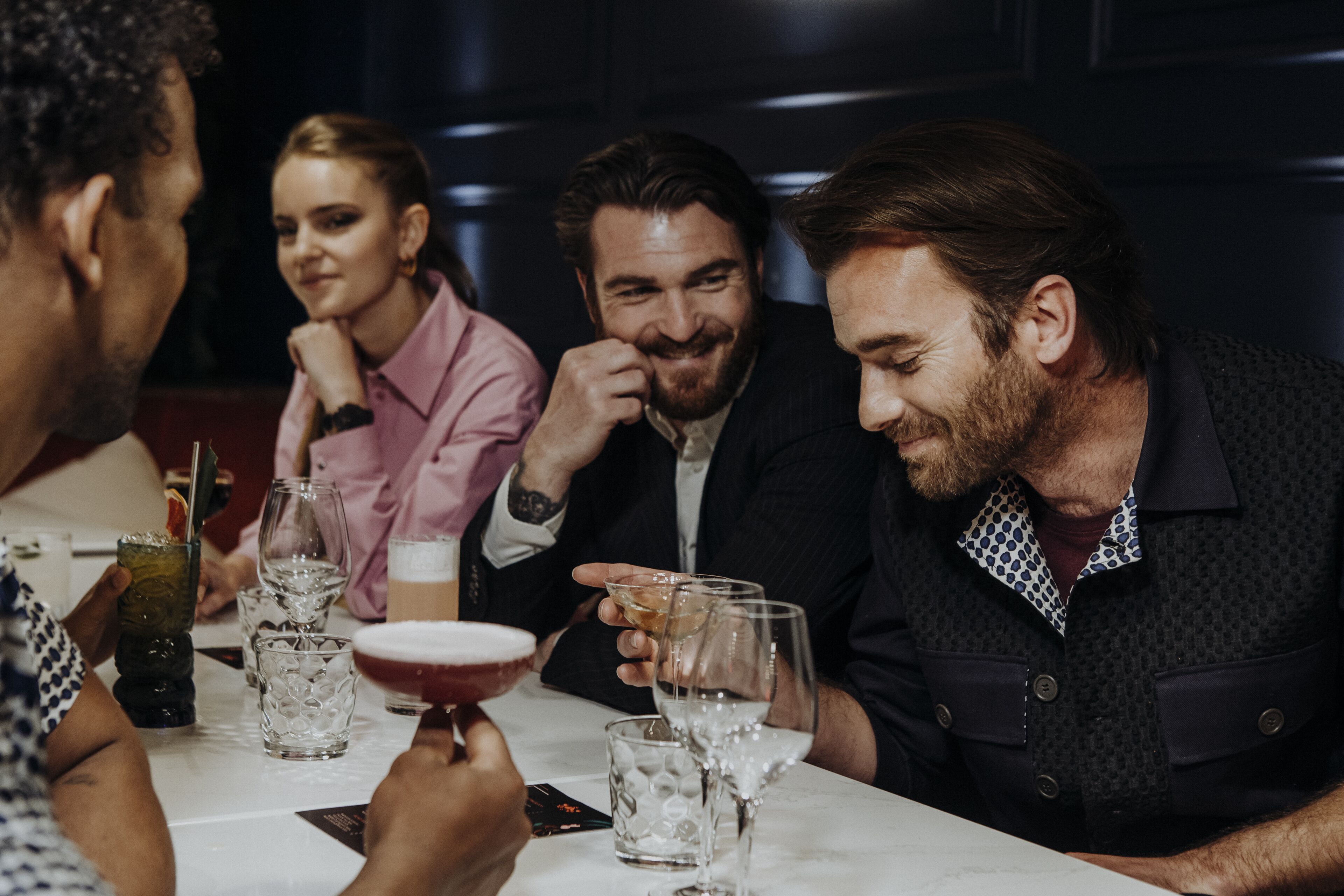 Un grupo de personas sentadas en una mesa con bebidas y vasos.