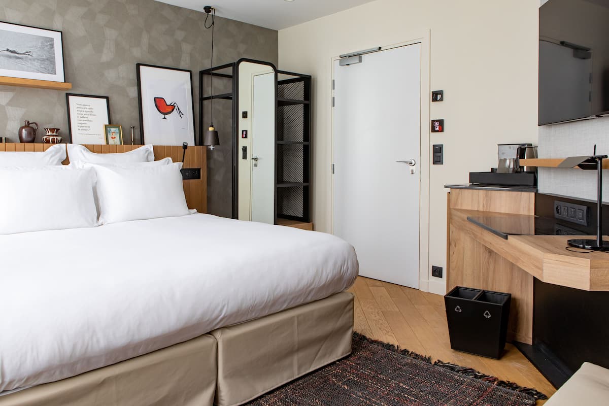 Una habitación de hotel moderna con una cama grande, un escritorio con televisión de pantalla plana, un armario y una pequeña kitchenette.