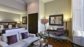 A hotel room with a bed, a sofa, a desk, and a chair.