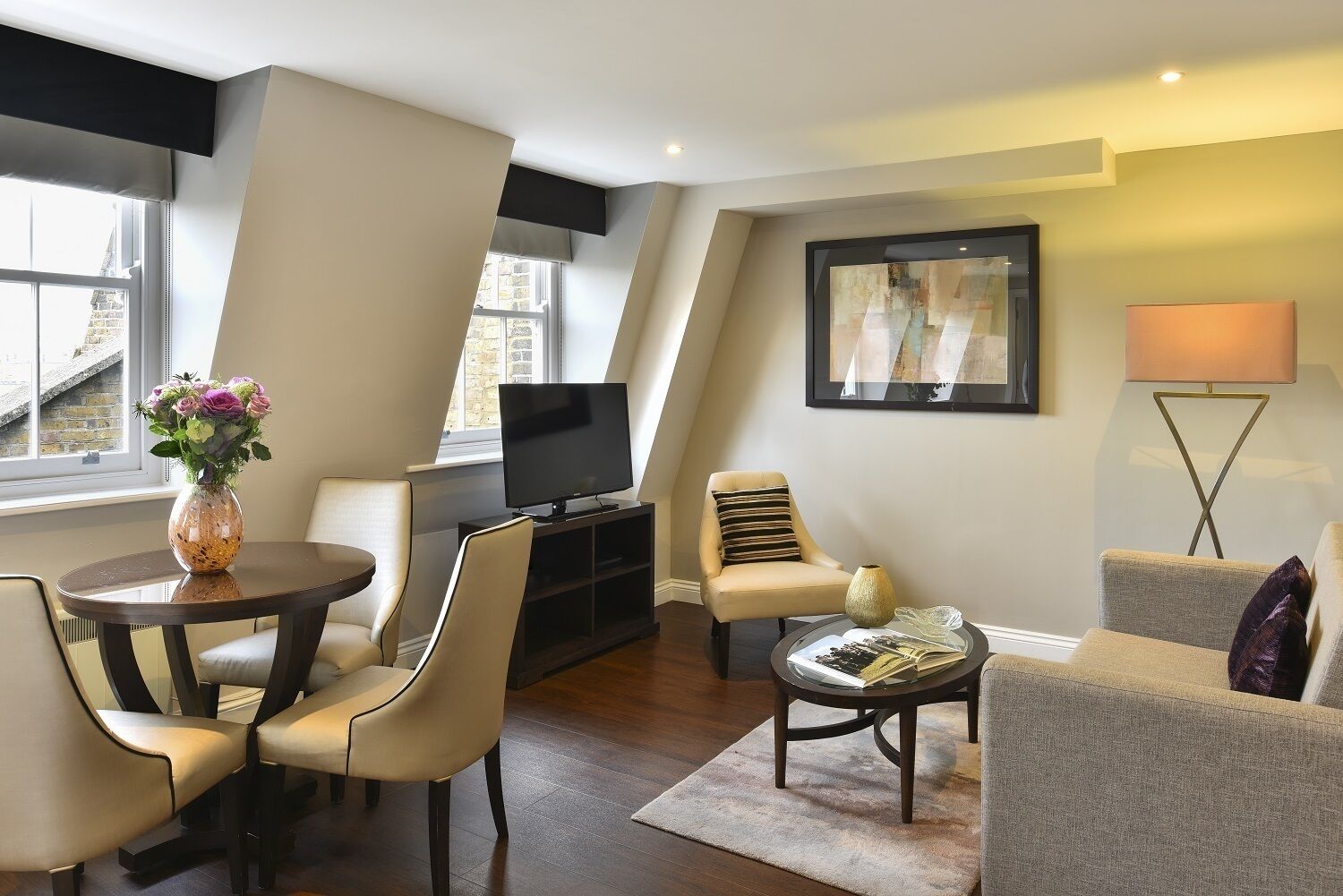 Un salon moderne doté d’un téléviseur à écran plat, de sièges confortables, d’une table basse et d’un vase de fleurs.