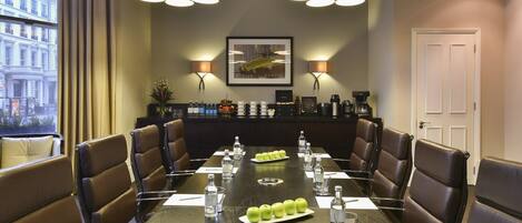 A conference room with a long table, brown leather chairs, and two pendant lights.