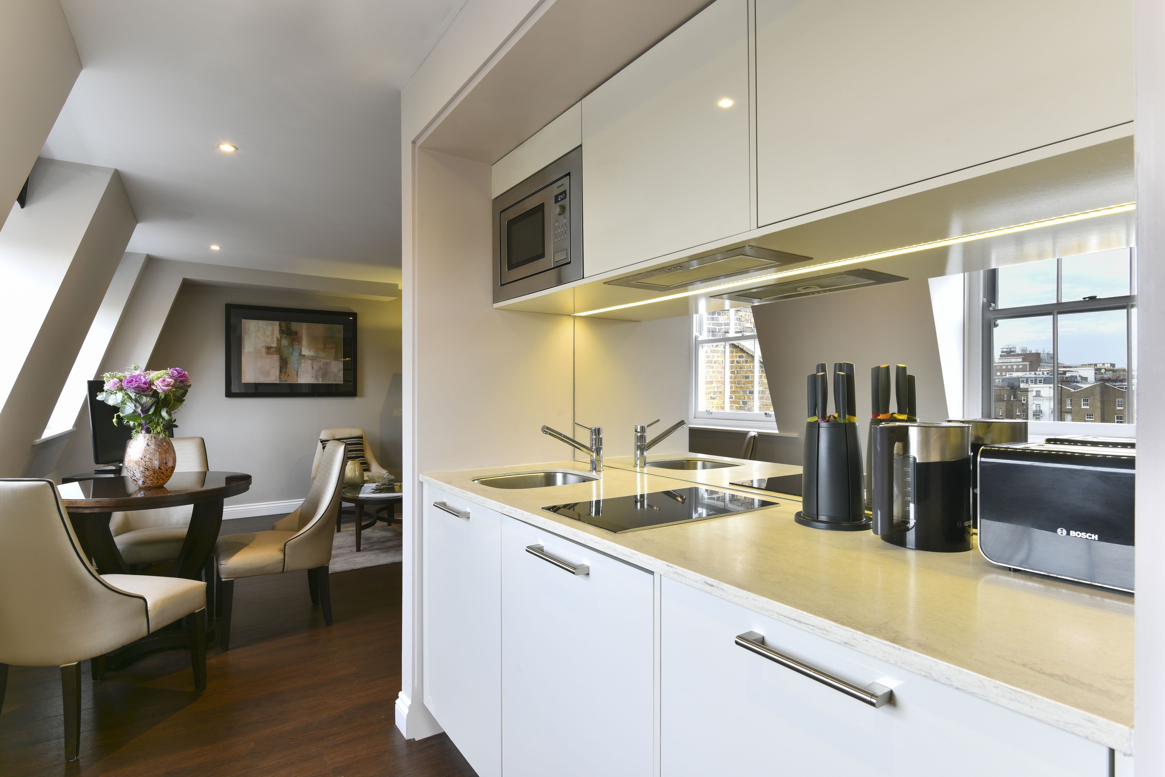 Una cocina moderna con armarios blancos, un lavamanos de acero inoxidable y un tostador Bosch.