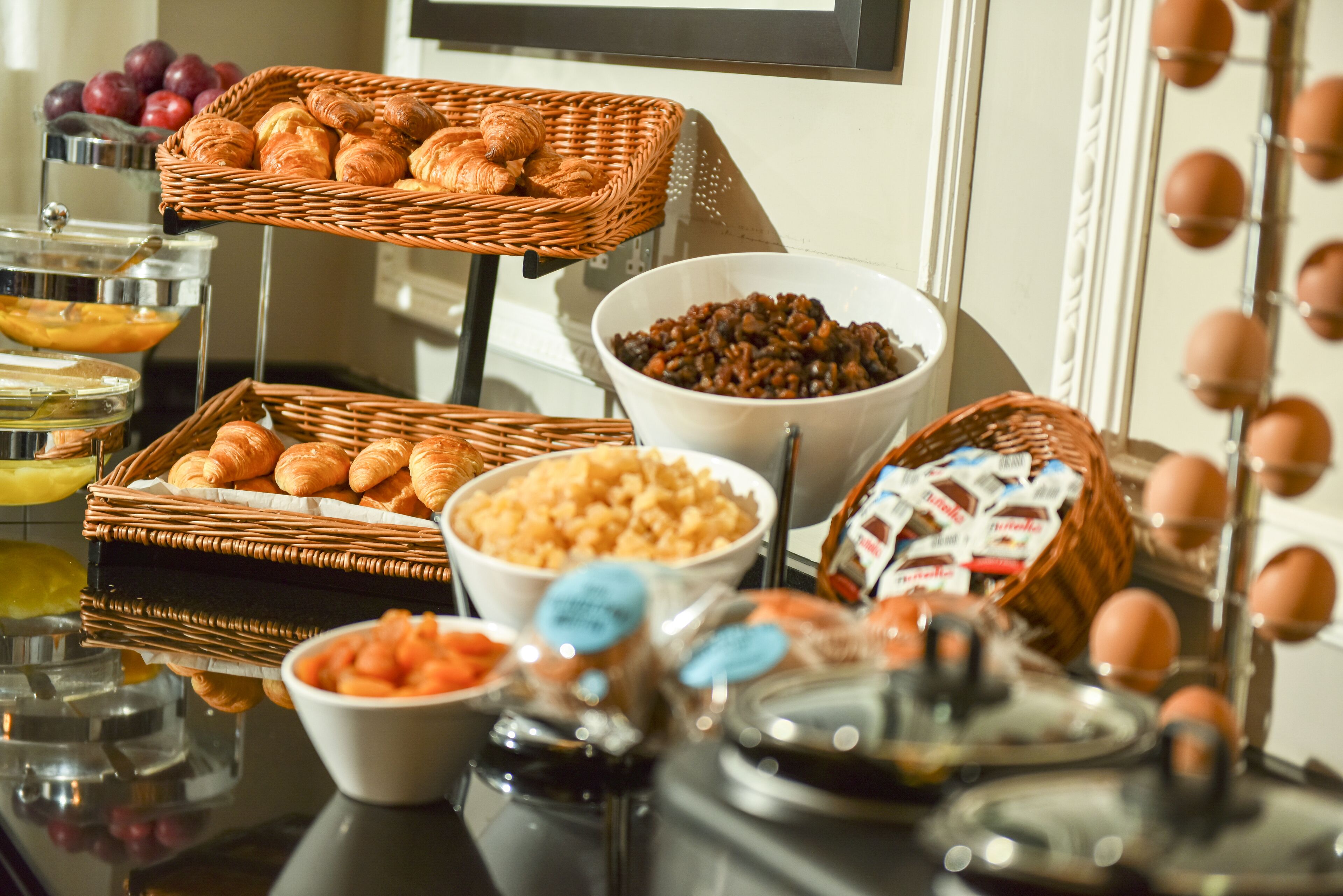 A buffet with various food items including pastries, fruits, and condiments.