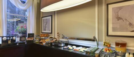 A buffet setup with various food items and a beverage dispenser.