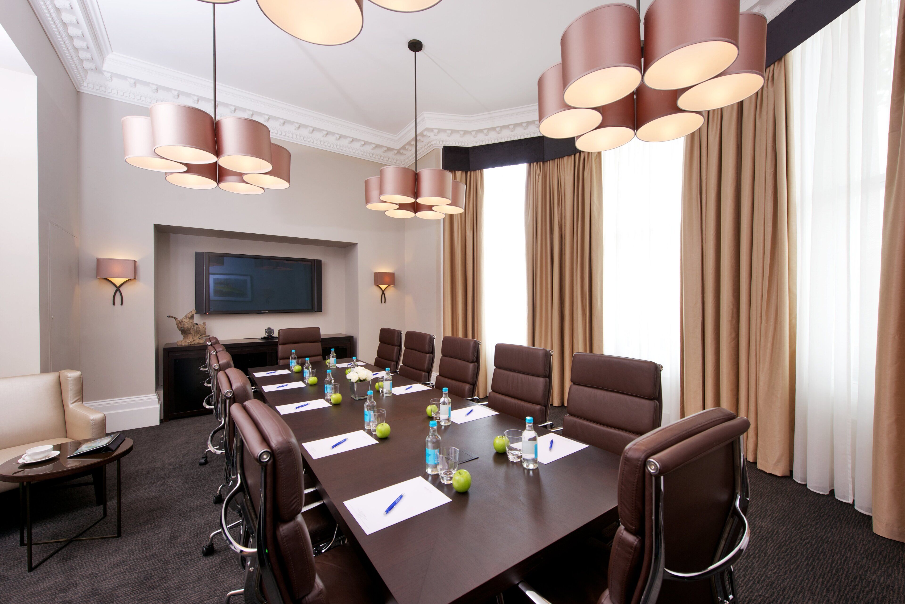 A conference room with a long table, multiple chairs, and a television screen.