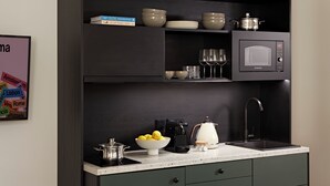 Una cocina con armarios oscuros, un microondas, un lavabo y diversos utensilios de cocina.