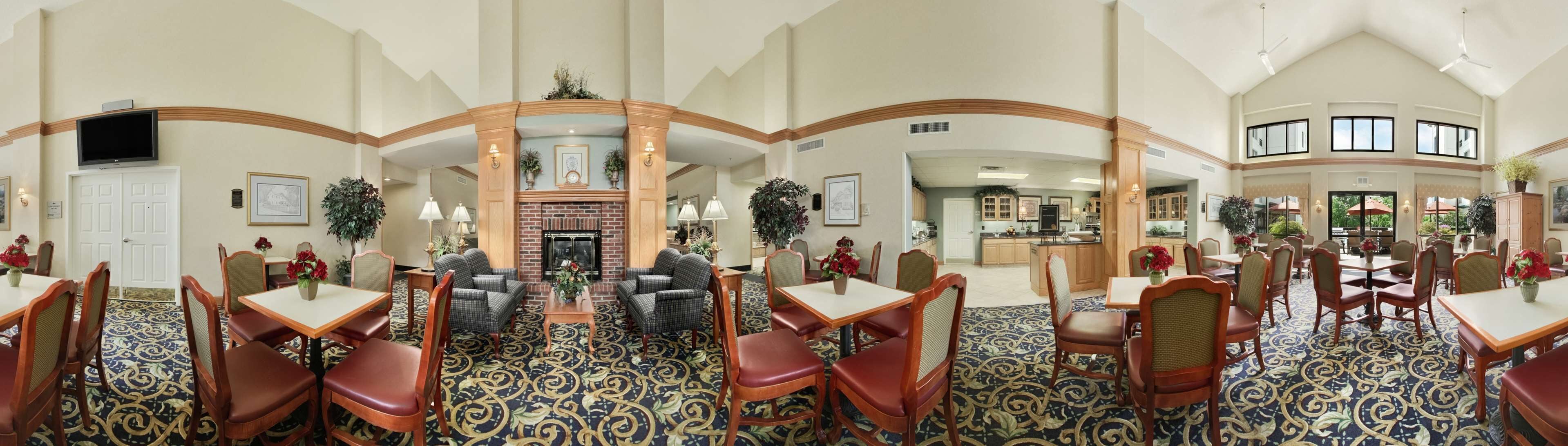 A hotel lobby with a fireplace, dining area, and kitchen.