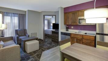 A hotel room with a living area, kitchenette, and a bed.