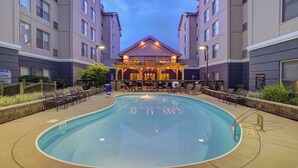 A pool area with lounge chairs and a covered seating area.