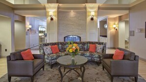 A living room with a sectional sofa, two armchairs, a round coffee table, and a fireplace.