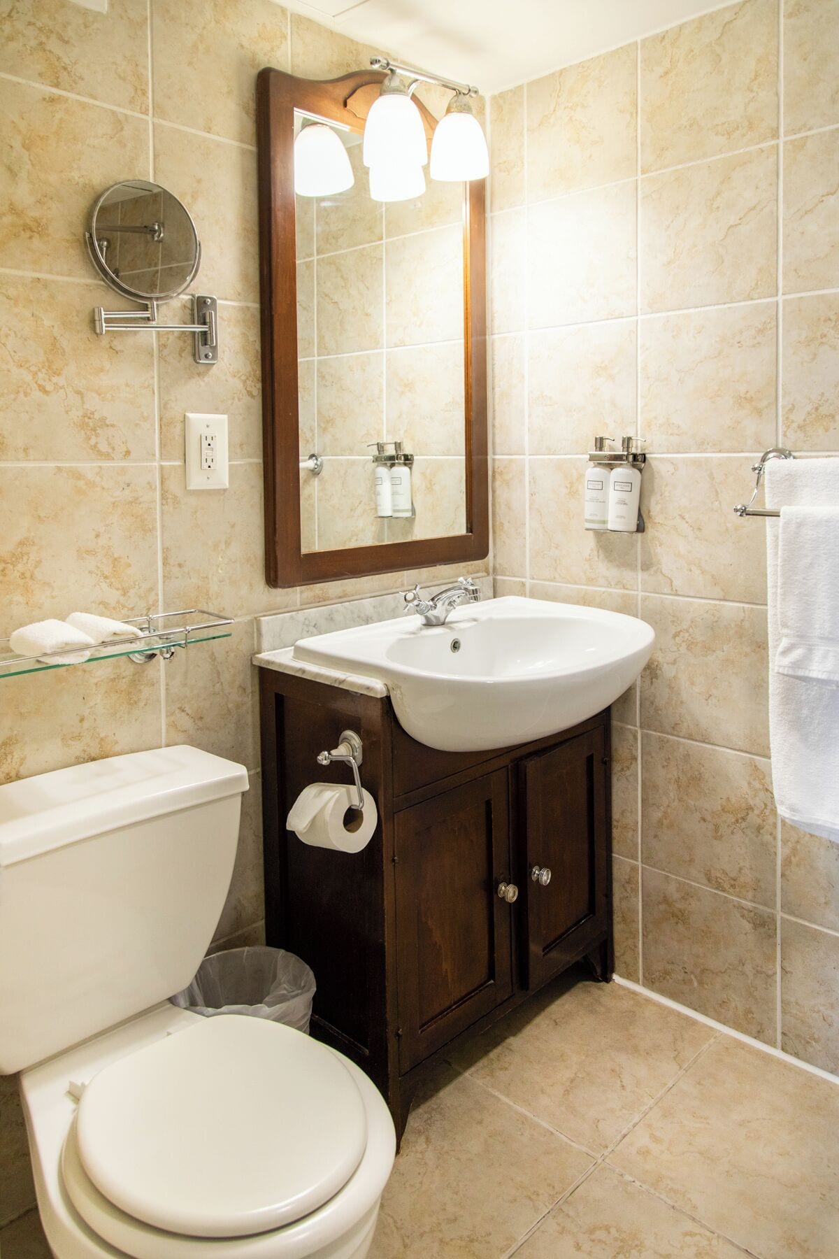 A bathroom with a toilet, sink, mirror, and towel rack.