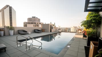 A rooftop pool with a clear view of the city skyline, including modern buildings and a circular structure.
