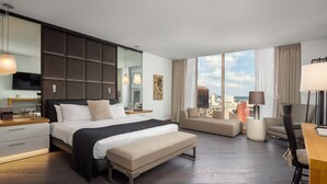 Una habitación de hotel moderna con una cama grande, un sofá, un escritorio y vistas a la ciudad.