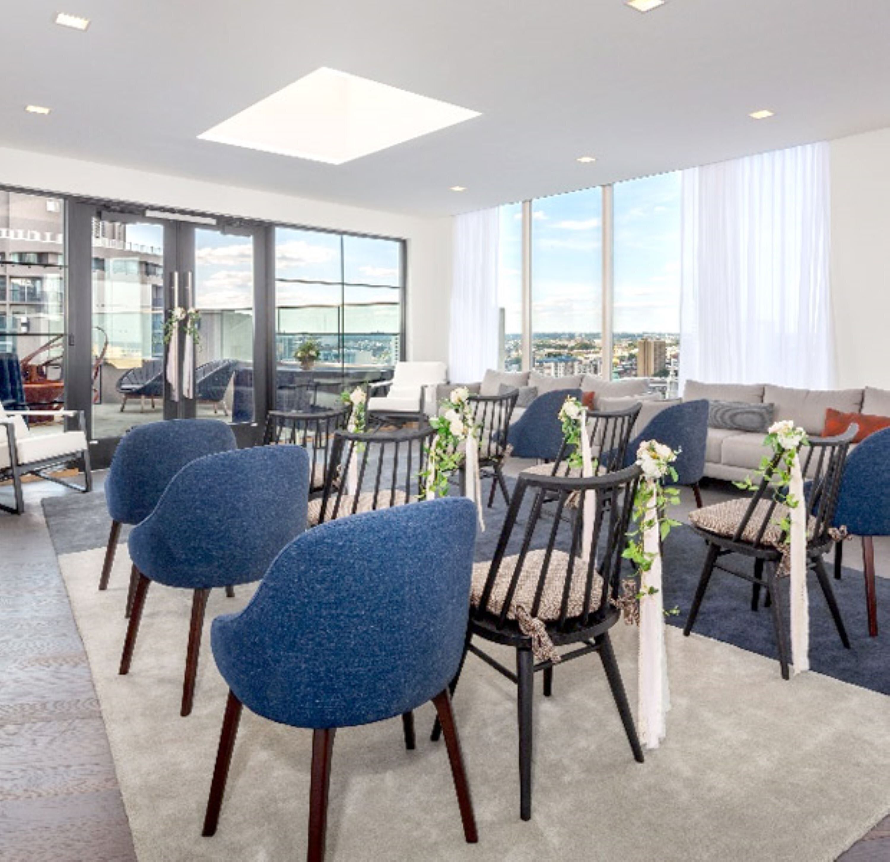A modern conference room with a city view, large windows, and blue chairs.