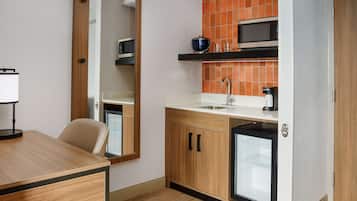 A compact kitchen with a microwave, sink, and a small refrigerator.