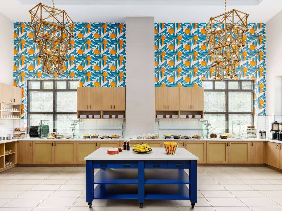 A modern kitchen with a central island, wooden cabinets, and a patterned wall.