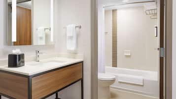 Un baño moderno con lavamanos, espejo y retrete.