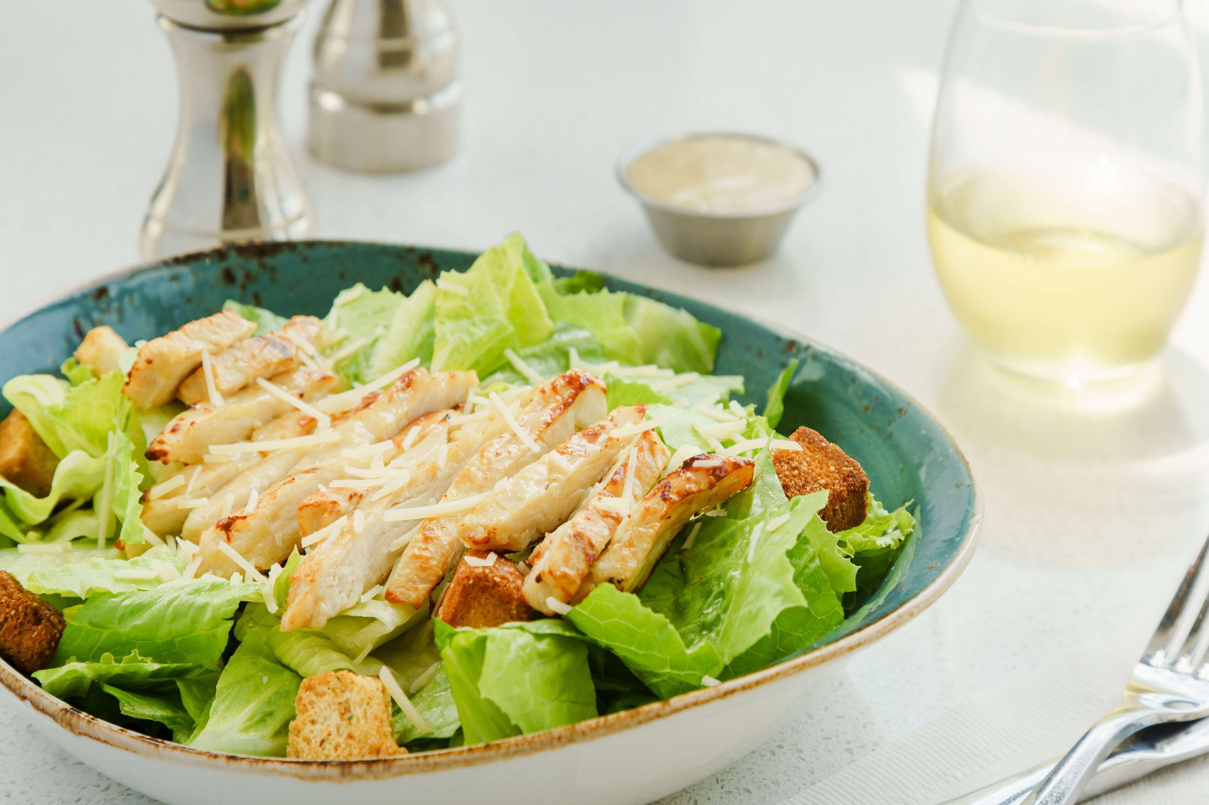 A bowl of salad with croutons and shredded cheese.