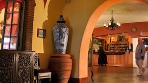 Un interior con una zona de bar, un jarrón grande y una estatua.
