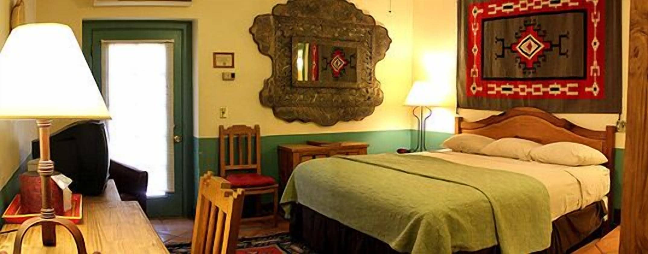 A traditional room with a bed, a chair, a table, and a lamp.