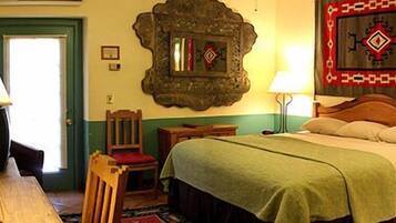 A traditional room with a bed, a chair, a table, and a lamp.