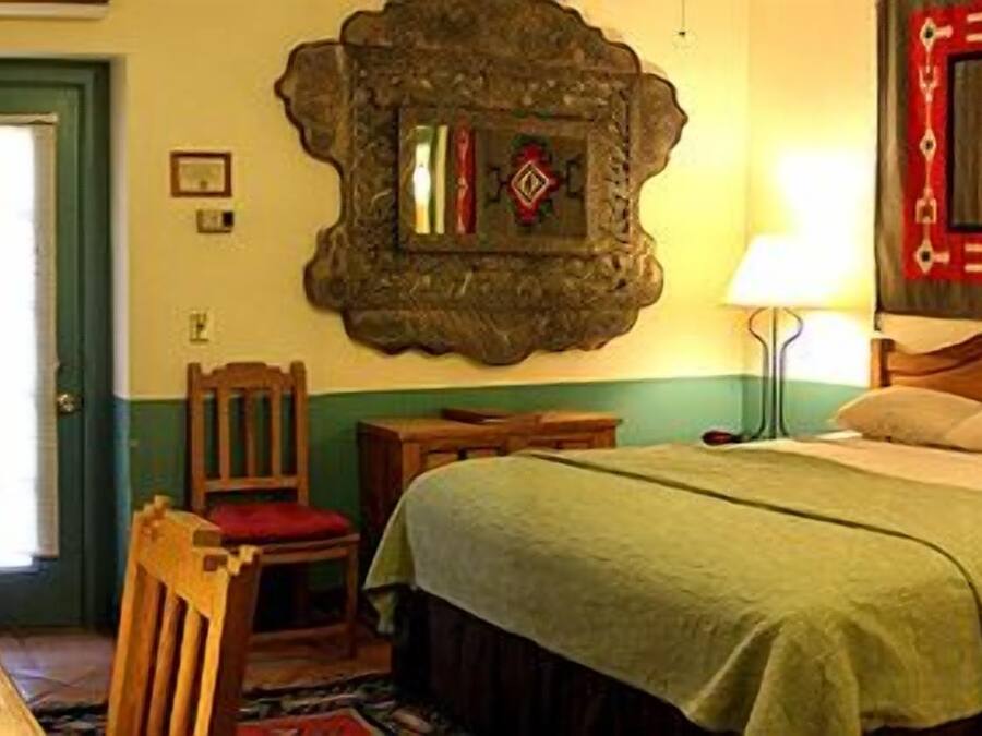 A traditional room with a bed, a chair, a table, and a lamp.