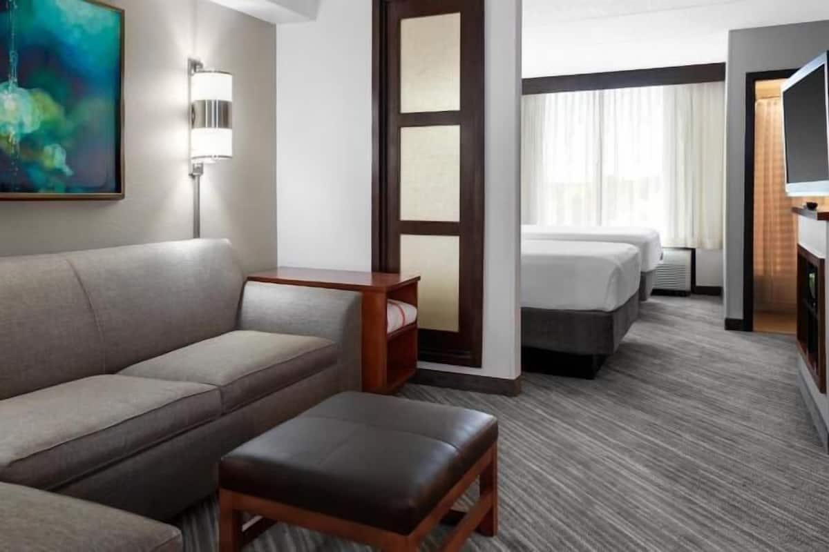 Ein Hotelzimmer mit einer Couch, einem kleinen Tisch, einem Fernseher und einem Bett.