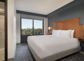 Habitación de hotel con una cama grande, vista a un parque y una ventana que da al circuito de montañas rusas.