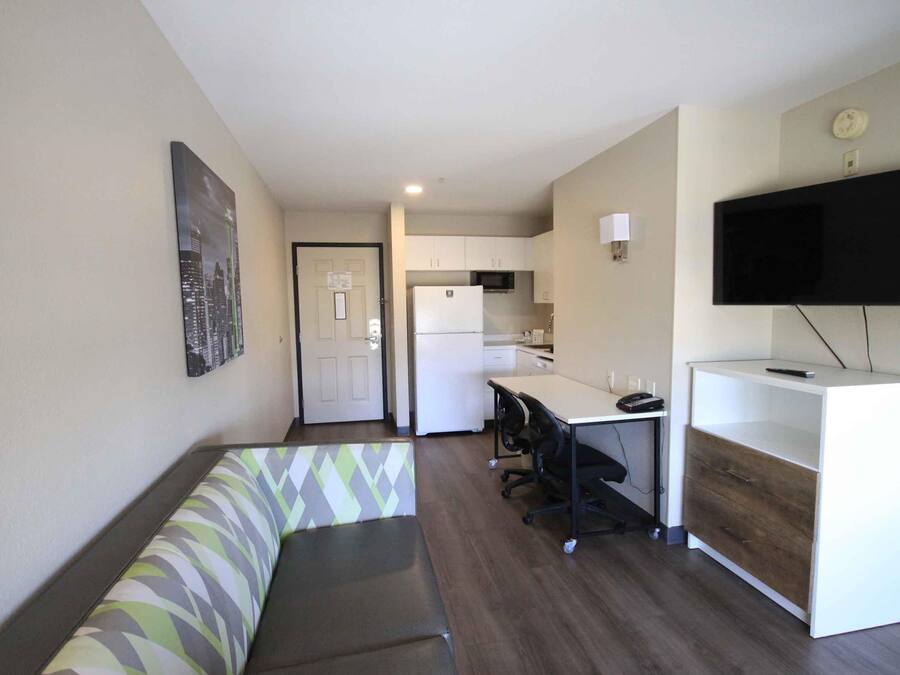 A compact living space with a kitchenette, a dining area, and a seating area with a patterned bench.