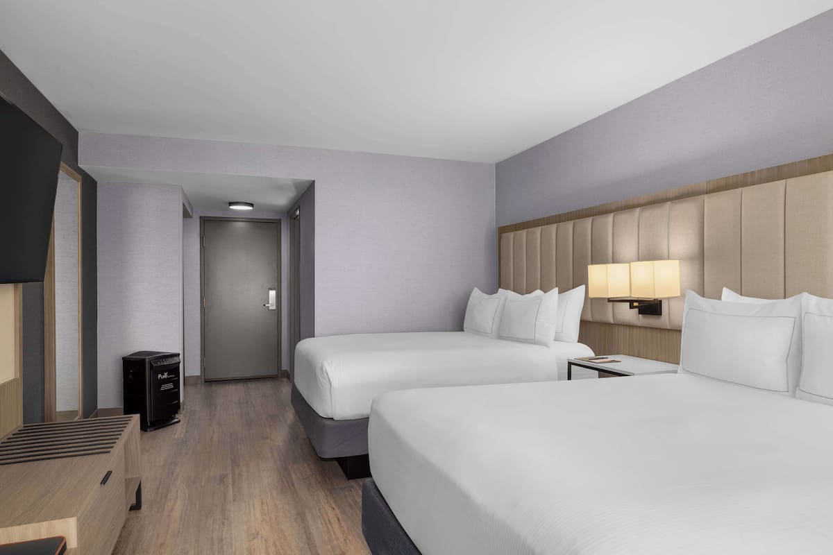 Una habitación de hotel con dos camas, televisión, escritorio y lámpara.
