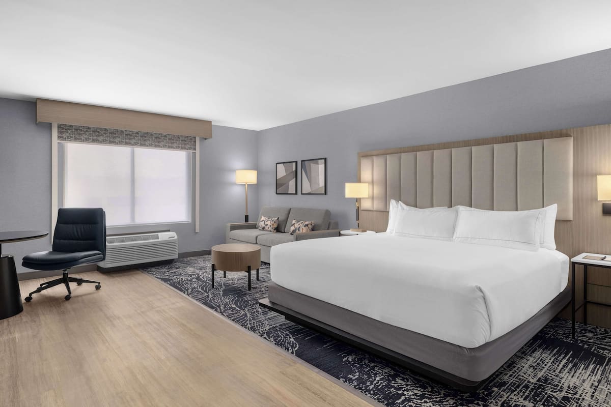 Habitación de hotel con una cama grande, un escritorio, una silla, un sofá y una mesita.