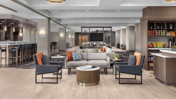 Eine moderne Hotelhalle mit Sitzgelegenheiten, einer Bar und einer Küchenzeile.