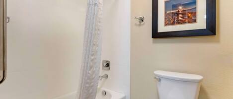 Een badkamer met een bad, toilet en een lijst met een afbeelding.
