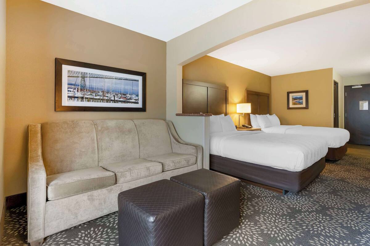 Ein Hotelzimmer mit einer Couch, einem Bett, einem Nachttisch und einer Lampe.