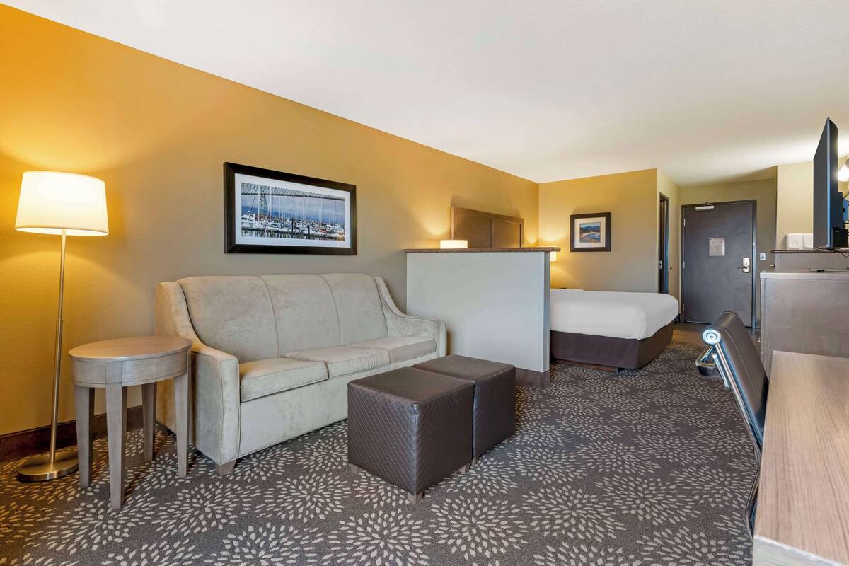 Ein Hotelzimmer mit einer Couch, einem Bett, einem kleinen Tisch und einem Schreibtisch mit Stuhl.