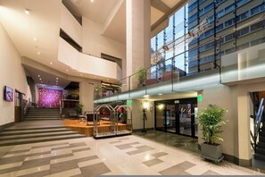 A spacious lobby with a central staircase, a seating area, and a view of the building's exterior. - Crowne Plaza Lima - Miraflores by IHG (Lima)