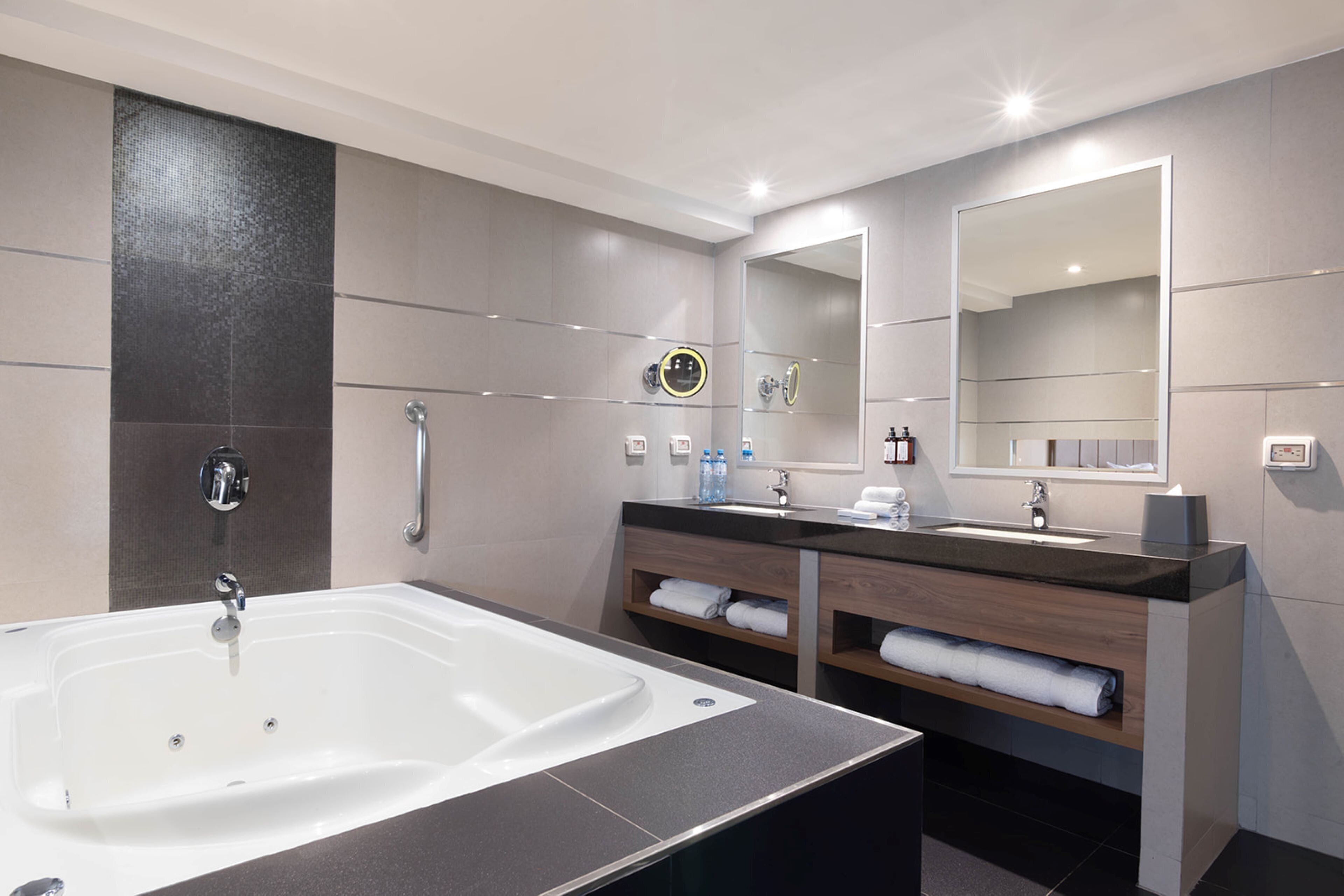 Ein modernes Badezimmer mit einer großen Badewanne, zwei Waschbecken und einem Waschtisch mit Stauraum.