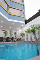 Una piscina al aire libre, sillones reclinables de piscina