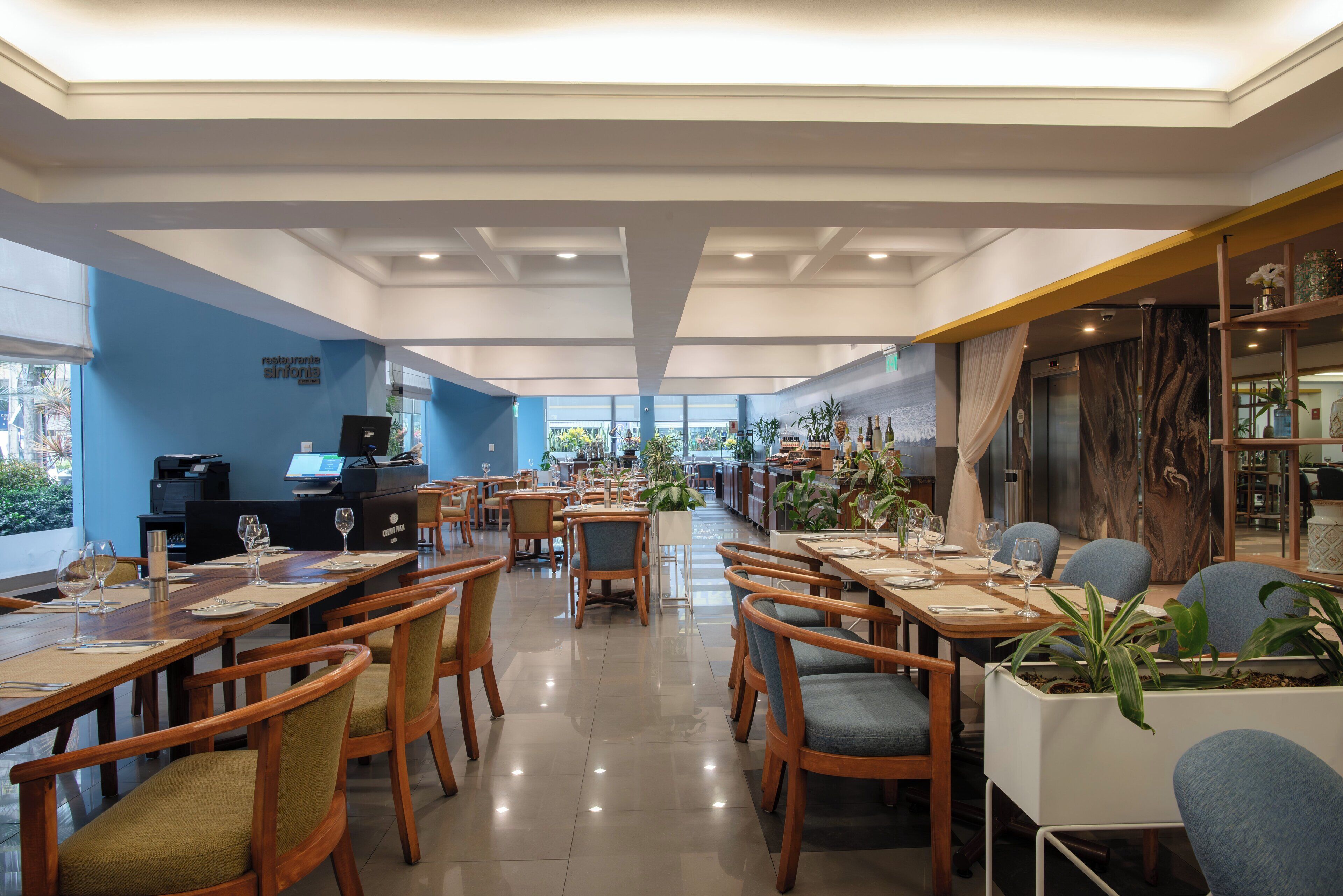 A spacious restaurant with wooden tables and chairs, a bar area, and a view of the outdoors.